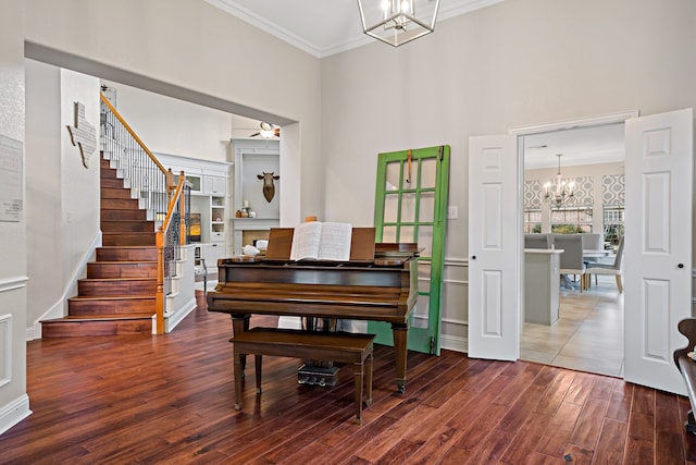 misc room featuring crown molding, dark wood-type flooring, and ceiling fan with notable chandelier