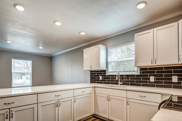 kitchen with kitchen peninsula, plenty of natural light, white cabinets, and sink