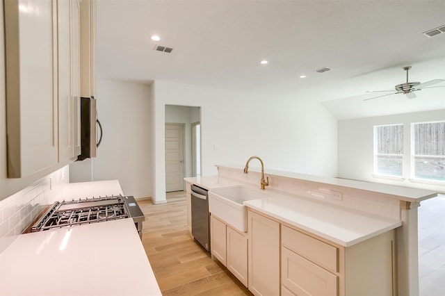 kitchen featuring decorative backsplash, appliances with stainless steel finishes, light wood-type flooring, ceiling fan, and sink