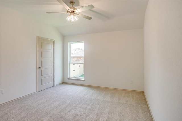 spare room with light colored carpet, vaulted ceiling, and ceiling fan