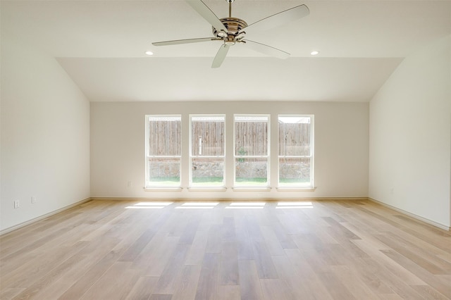 unfurnished room featuring light wood-type flooring, vaulted ceiling, plenty of natural light, and ceiling fan