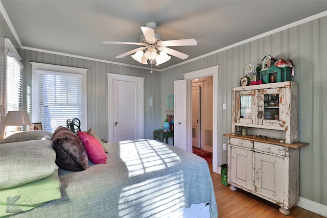 bedroom with light wood-type flooring, ceiling fan, and crown molding