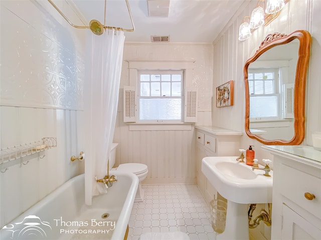 bathroom with toilet, shower / tub combo with curtain, and crown molding