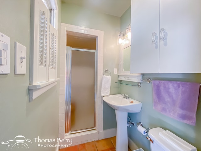 bathroom featuring toilet and a shower with shower door