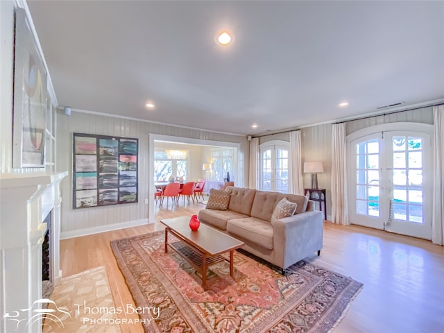 living room with light hardwood / wood-style floors, ornamental molding, and french doors