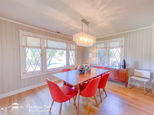 dining room with light hardwood / wood-style floors, ornamental molding, and an inviting chandelier