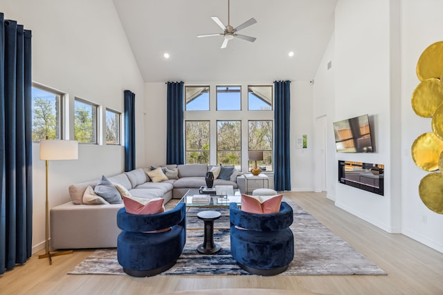 living room with light hardwood / wood-style flooring, high vaulted ceiling, and ceiling fan