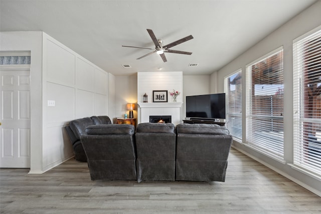 living room featuring ceiling fan, light hardwood / wood-style floors, and a tile fireplace