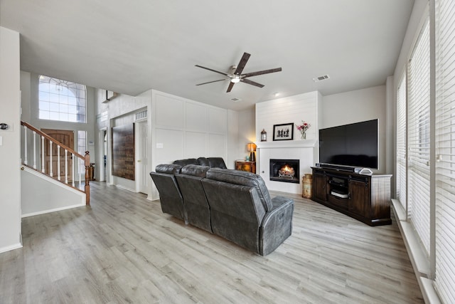 living room with a fireplace, light hardwood / wood-style floors, and ceiling fan