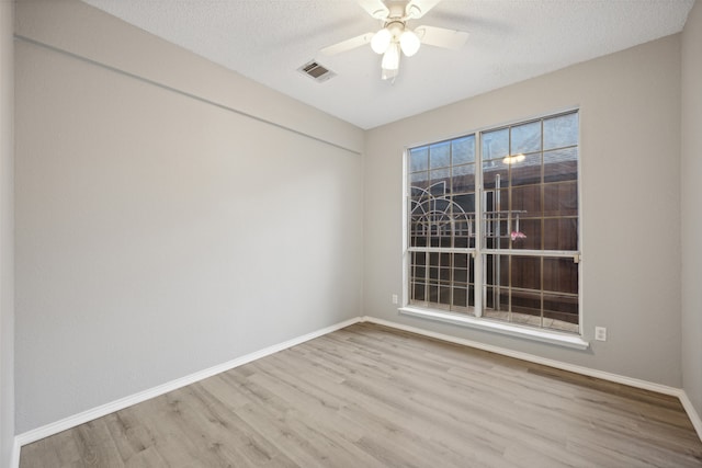 unfurnished room with ceiling fan, a textured ceiling, and light wood-type flooring