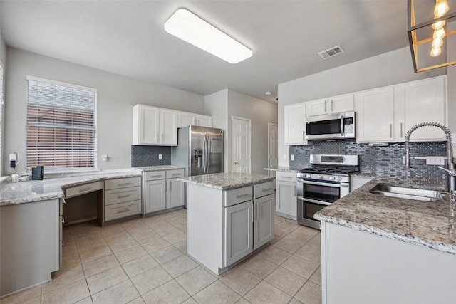 kitchen featuring white cabinets, sink, a kitchen island, and appliances with stainless steel finishes