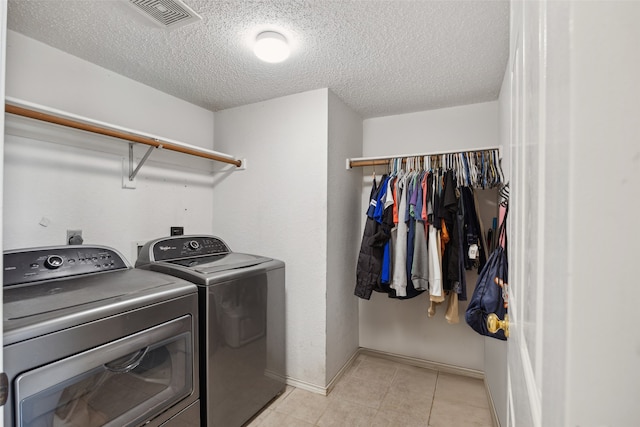 laundry room featuring independent washer and dryer, a textured ceiling, and light tile patterned floors