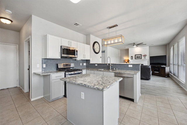 kitchen with ceiling fan, a center island, hanging light fixtures, kitchen peninsula, and appliances with stainless steel finishes