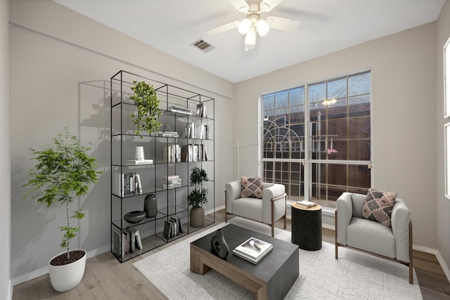 living area with hardwood / wood-style floors, a textured ceiling, and ceiling fan