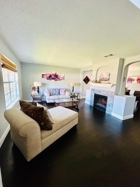 living room with a stone fireplace and a textured ceiling