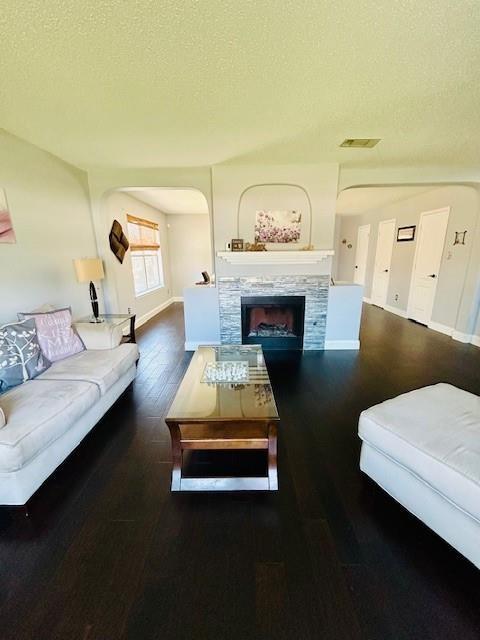 living room with a fireplace, a textured ceiling, and dark hardwood / wood-style floors