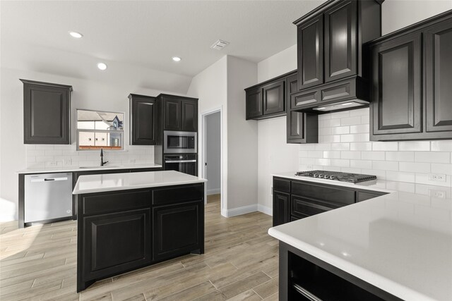 kitchen featuring decorative backsplash, a center island, light hardwood / wood-style floors, and appliances with stainless steel finishes