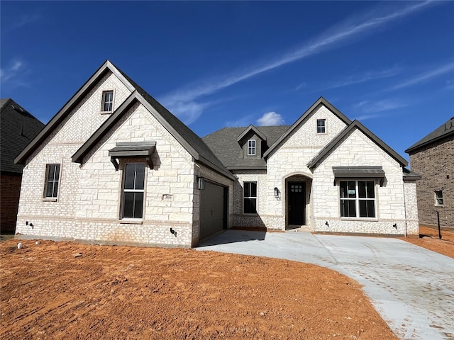 french provincial home with a garage and a front lawn