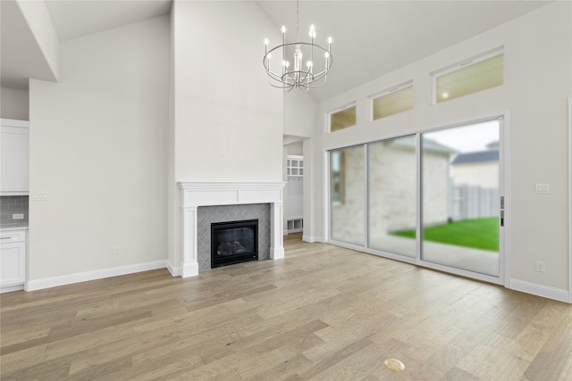 3208 Andesite Rd, Mckinney, TX 75071 - unfurnished living room with high vaulted ceiling, a chandelier, light wood finished floors, a tile fireplace, and baseboards