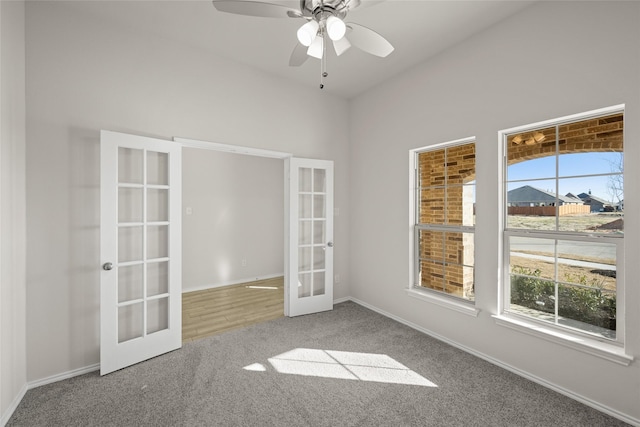 carpeted spare room featuring ceiling fan and french doors