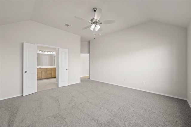 unfurnished bedroom featuring ceiling fan, ensuite bathroom, vaulted ceiling, and light carpet