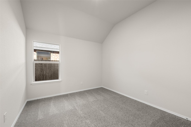 carpeted empty room with lofted ceiling