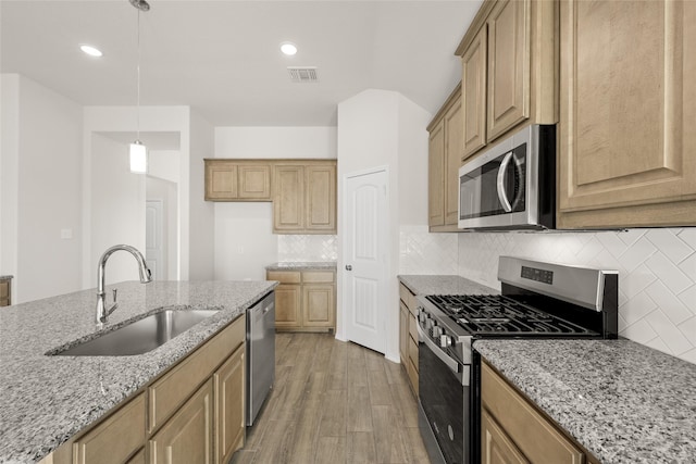 kitchen featuring sink, decorative light fixtures, stainless steel appliances, light stone countertops, and decorative backsplash