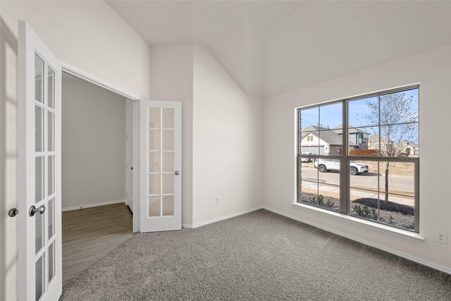 carpeted empty room featuring lofted ceiling and french doors