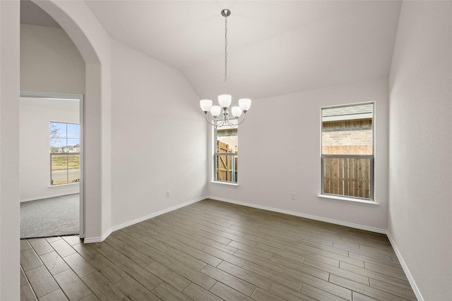 spare room with an inviting chandelier, dark hardwood / wood-style flooring, and vaulted ceiling