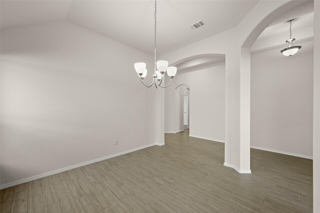 spare room with dark hardwood / wood-style flooring, lofted ceiling, and an inviting chandelier