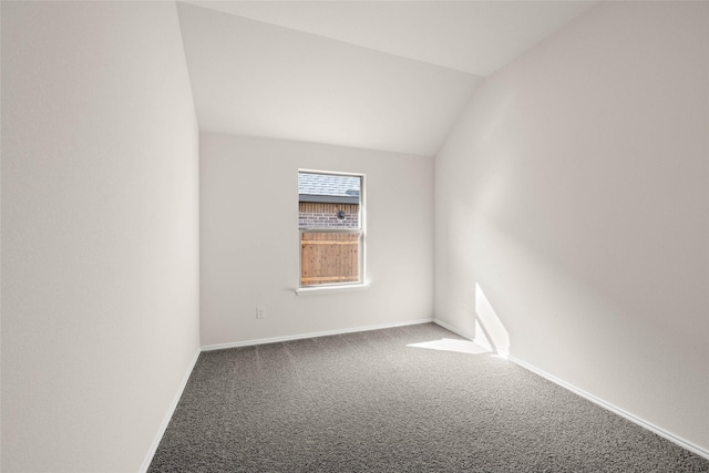 carpeted empty room with vaulted ceiling