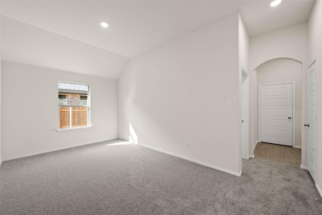 carpeted empty room with vaulted ceiling