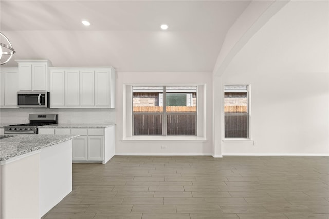 kitchen featuring light hardwood / wood-style flooring, white cabinetry, stainless steel appliances, light stone counters, and decorative backsplash