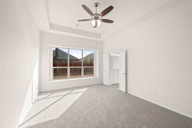 carpeted empty room with ceiling fan and a tray ceiling