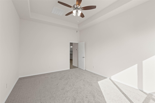 carpeted empty room with ceiling fan and a tray ceiling