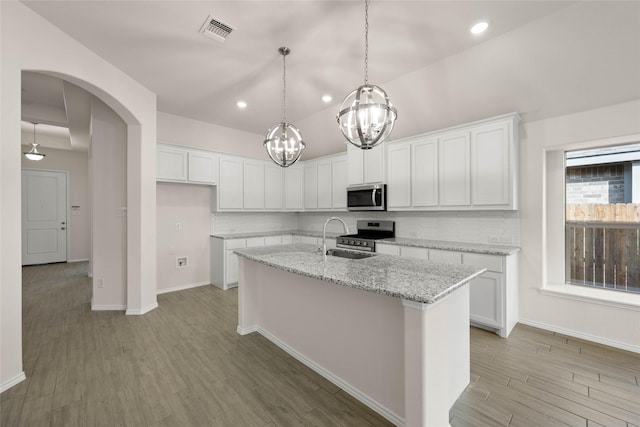 kitchen with stainless steel appliances, a kitchen island with sink, and white cabinets