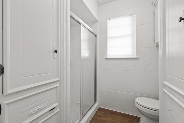 bathroom featuring tile walls, wood-type flooring, toilet, and walk in shower