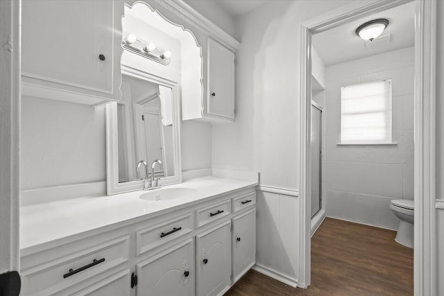 bathroom with toilet, hardwood / wood-style flooring, an enclosed shower, and vanity