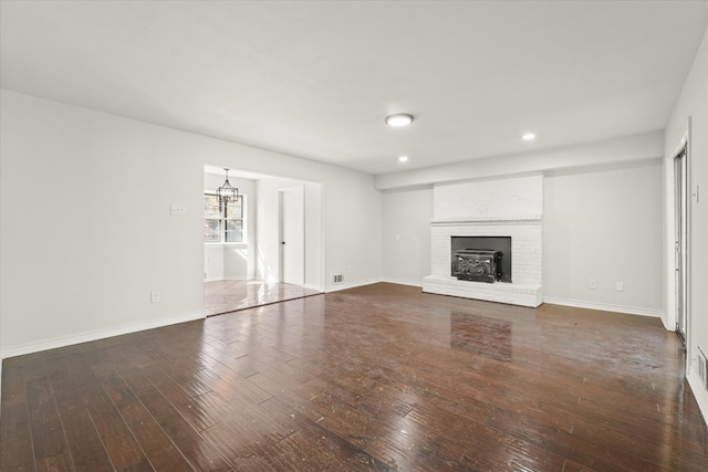 unfurnished living room with dark wood-type flooring and a brick fireplace