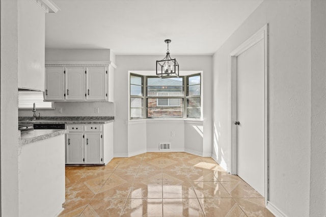 kitchen with pendant lighting, light tile patterned floors, white cabinetry, and a notable chandelier