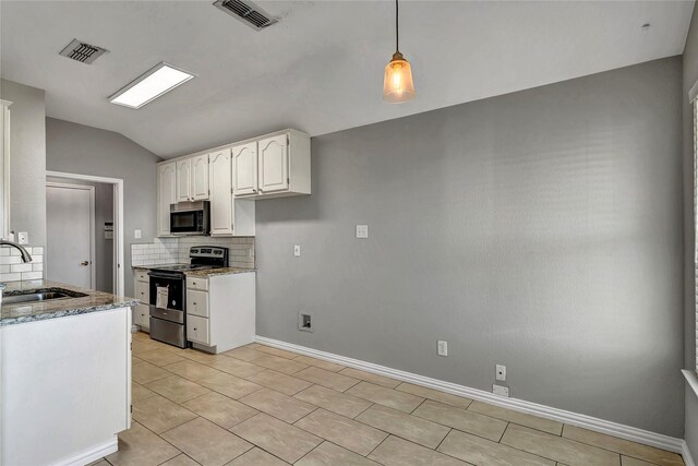 kitchen with decorative backsplash, stainless steel appliances, dark stone countertops, white cabinetry, and lofted ceiling