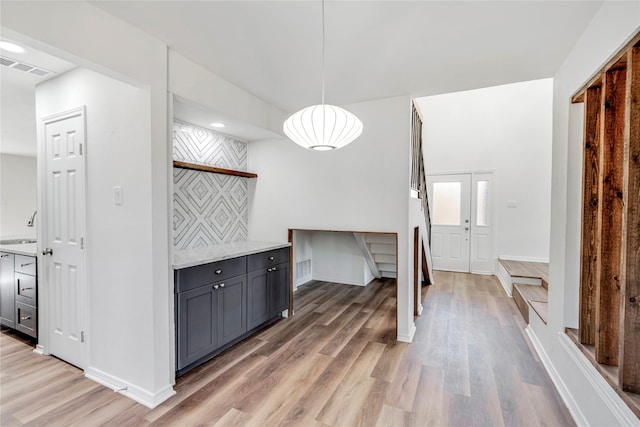 interior space with light stone counters, pendant lighting, wood-type flooring, and sink