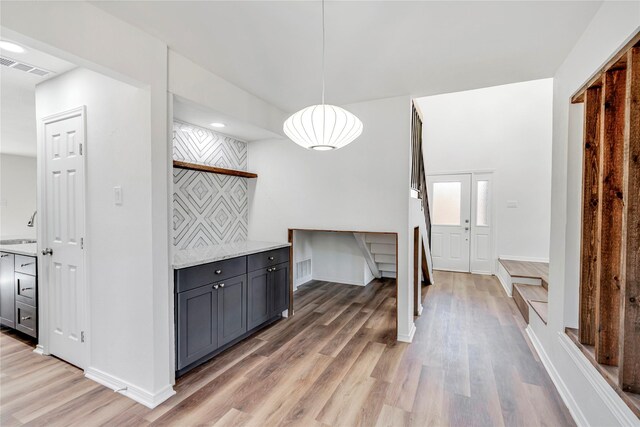 interior space with light stone counters, pendant lighting, wood-type flooring, and sink