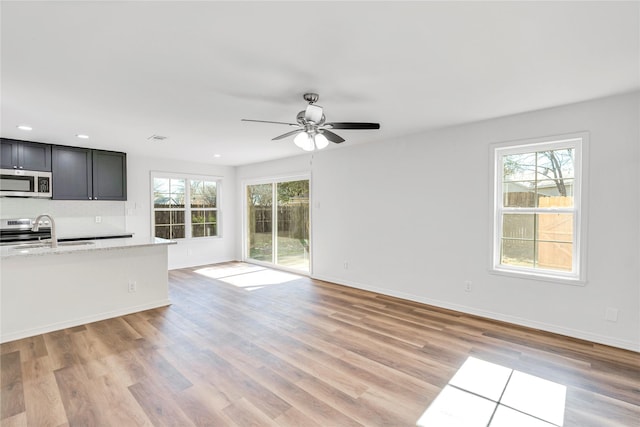 unfurnished living room with light wood-type flooring, ceiling fan, and sink