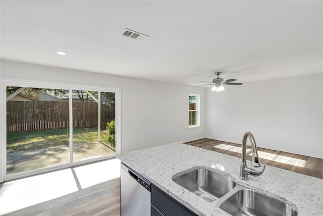 kitchen featuring wood-type flooring, light stone counters, stainless steel dishwasher, and sink