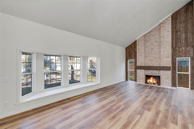 unfurnished living room with hardwood / wood-style flooring, high vaulted ceiling, and a brick fireplace