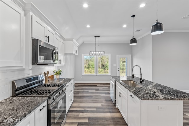 kitchen with sink, stainless steel appliances, tasteful backsplash, an island with sink, and white cabinets