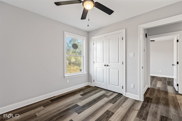 unfurnished bedroom with ceiling fan, dark wood-type flooring, and a closet