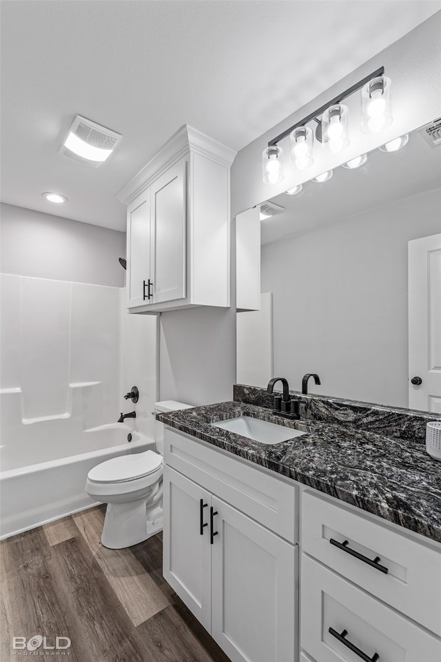 full bathroom featuring toilet, hardwood / wood-style floors, vanity, and bathing tub / shower combination