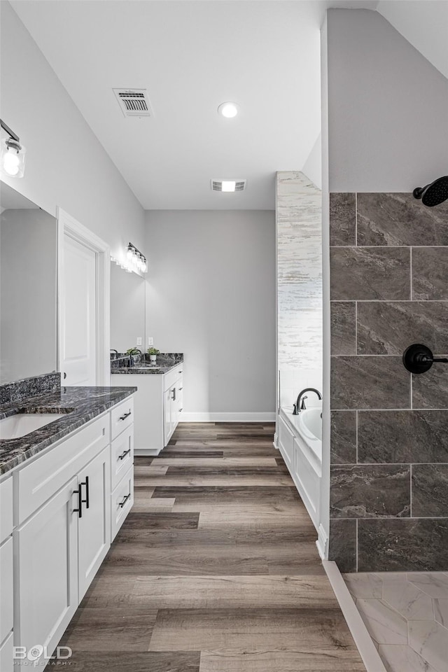 bathroom featuring hardwood / wood-style floors, vanity, and plus walk in shower